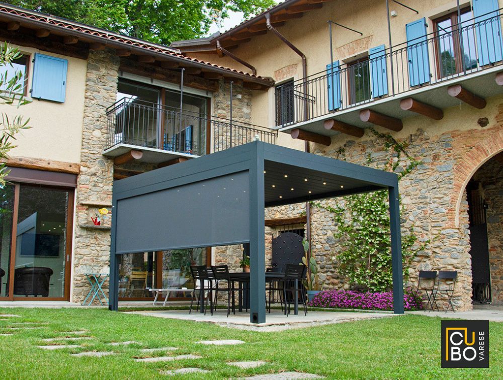 Installazione di un moderno pergolato bioclimatico in alluminio nel giardino di una villa rustica in provincia di Varese.